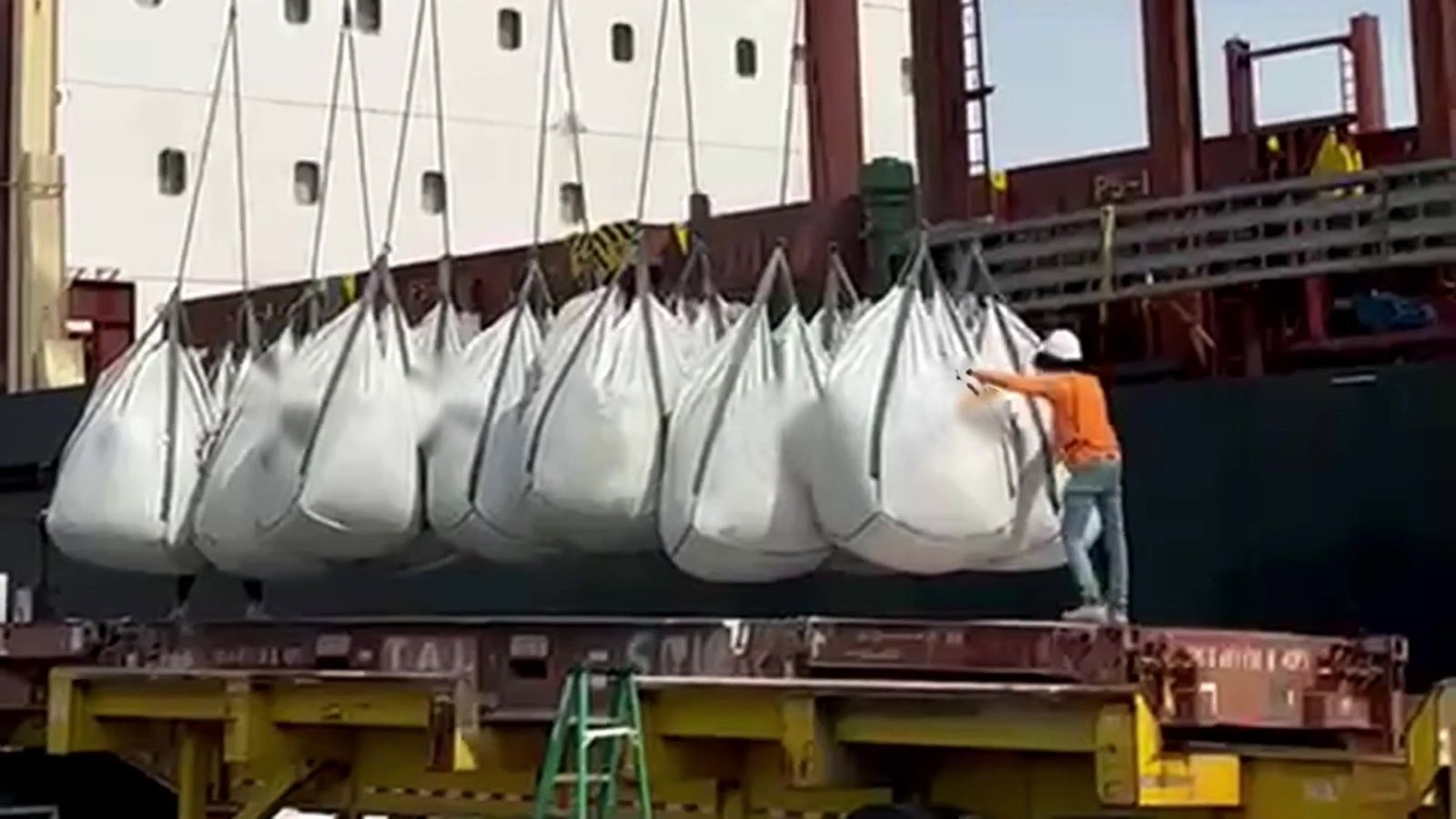 Longshoreman guiding a sling of jumbo bags onto a flatbed