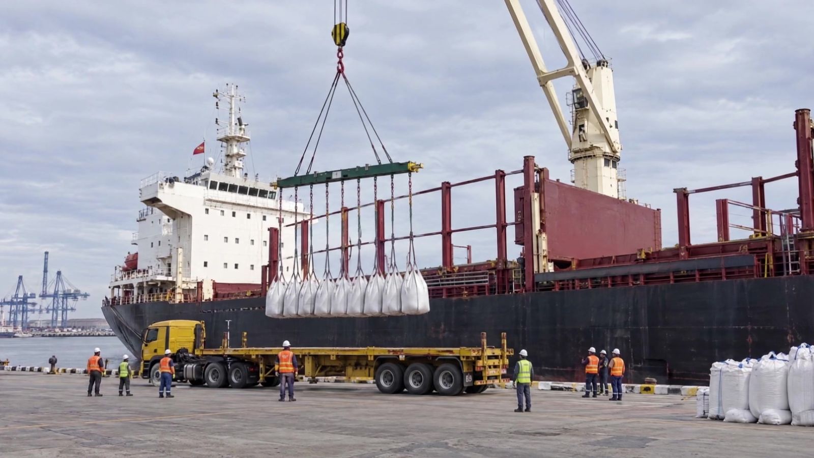 Crane lifting a row of jumbo bags off the ship onto a flatbed at the Port of Miami